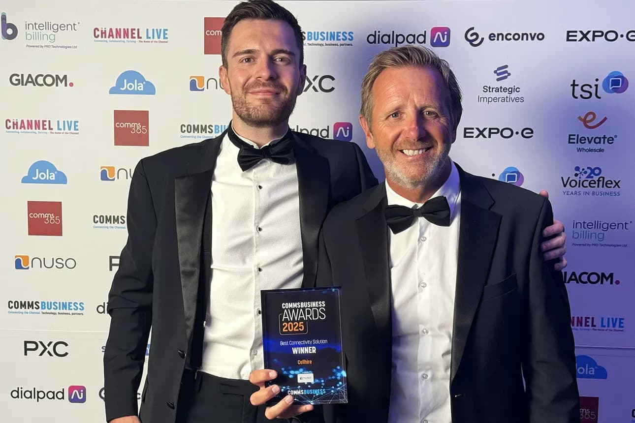 Two happy, distinguished gentlemen in suits hold a gleaming trophy at an award ceremony.